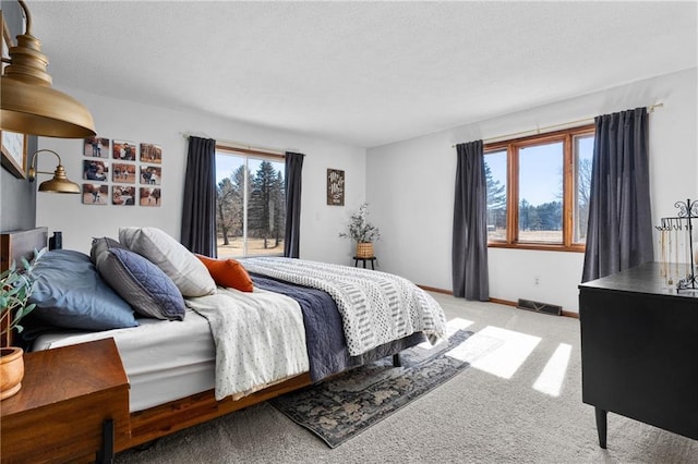 bedroom featuring light carpet, a textured ceiling, and baseboards