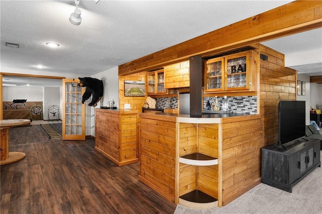 bar with dark wood-style floors, visible vents, a textured ceiling, a dry bar, and tasteful backsplash