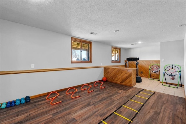 game room with visible vents, baseboards, a textured ceiling, and wood finished floors