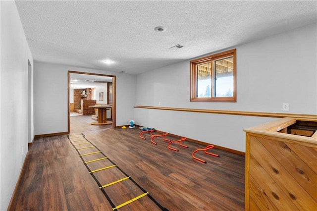 interior space with visible vents, a textured ceiling, baseboards, and wood finished floors