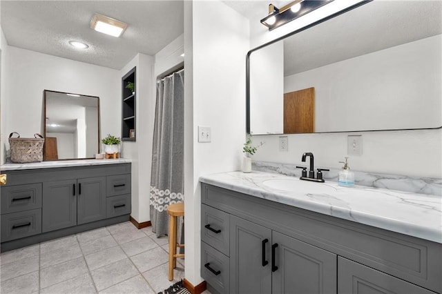 full bath with curtained shower, two vanities, tile patterned floors, a textured ceiling, and a sink