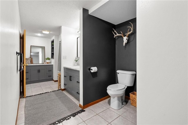 full bathroom featuring a textured ceiling, toilet, vanity, and tile patterned flooring