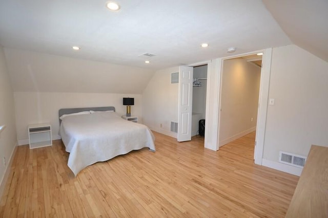 bedroom featuring lofted ceiling, light wood-style floors, visible vents, and baseboards