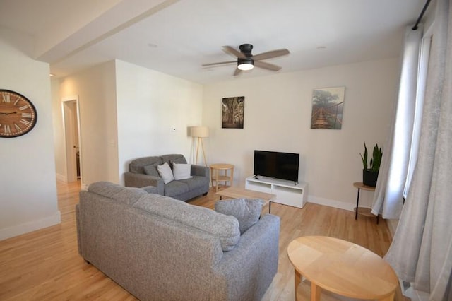 living area featuring baseboards, ceiling fan, and light wood finished floors