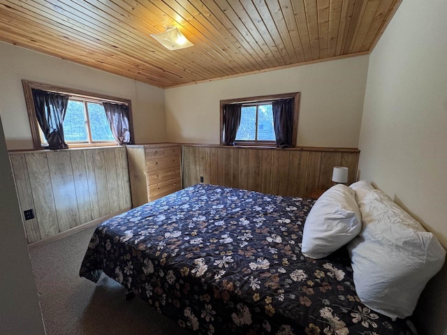 bedroom featuring multiple windows, carpet floors, wood ceiling, and wainscoting