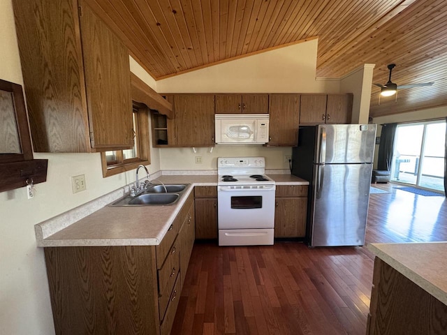 kitchen with white appliances, a sink, vaulted ceiling, dark wood-type flooring, and light countertops