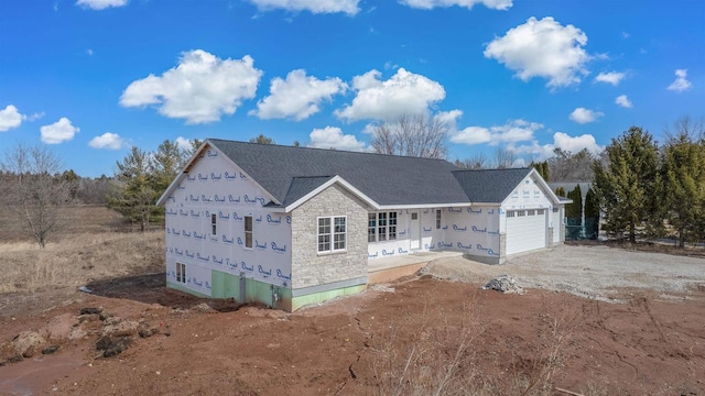 property in mid-construction featuring stone siding, driveway, an attached garage, and roof with shingles