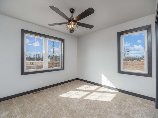 carpeted empty room featuring plenty of natural light, baseboards, and visible vents