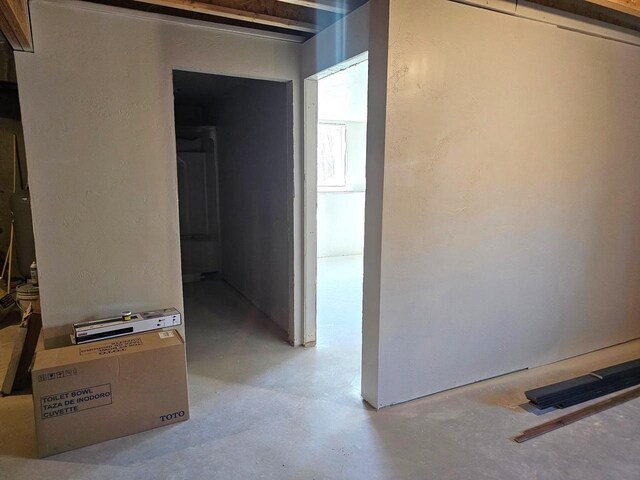hall featuring a textured wall and concrete floors