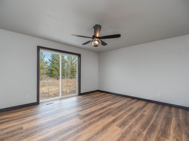 spare room featuring ceiling fan, visible vents, baseboards, and wood finished floors