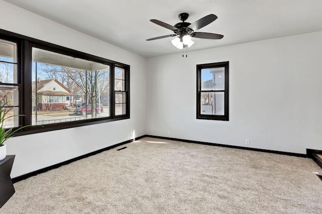 spare room featuring visible vents, carpet floors, baseboards, and ceiling fan