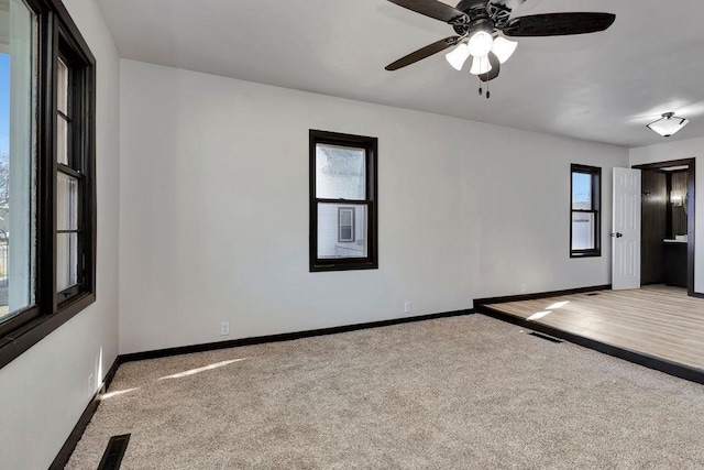 empty room with visible vents, a ceiling fan, baseboards, and carpet floors