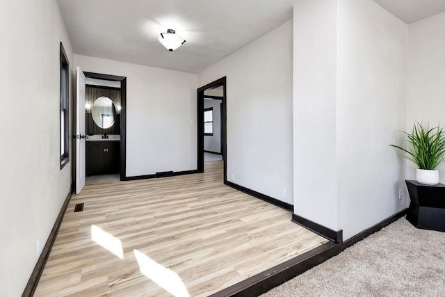 interior space featuring light wood-style floors, baseboards, and visible vents