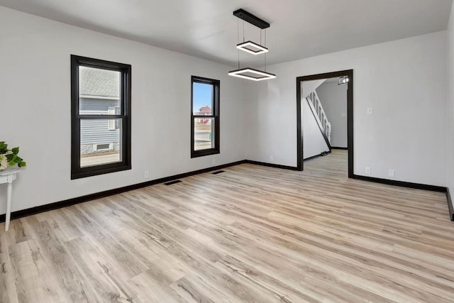 spare room with visible vents, light wood-style flooring, and baseboards