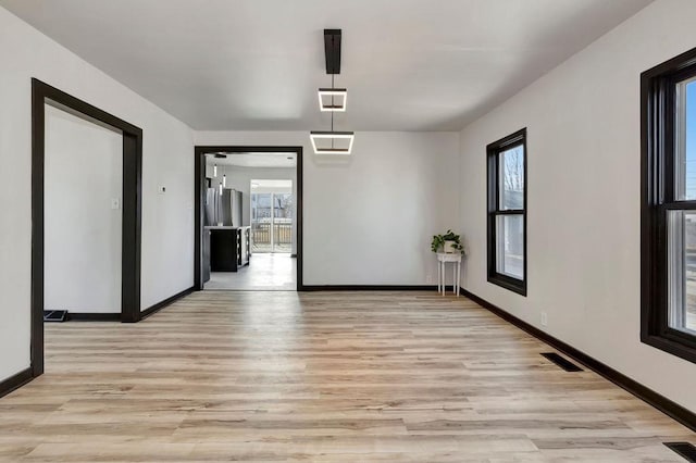 unfurnished dining area with light wood-style floors, visible vents, and baseboards