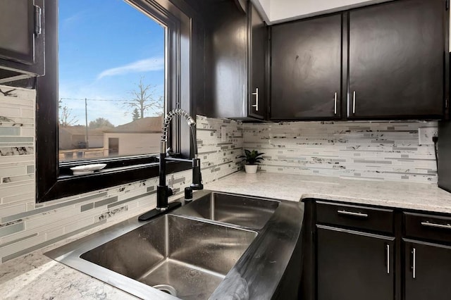 kitchen featuring light stone counters, tasteful backsplash, and a sink