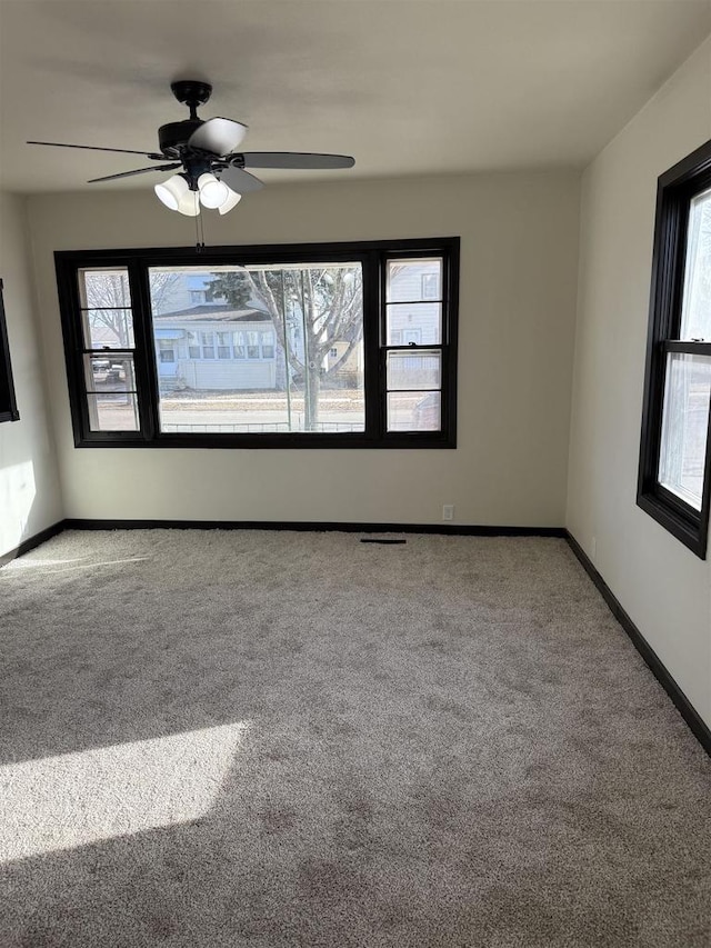 carpeted empty room featuring a ceiling fan and baseboards