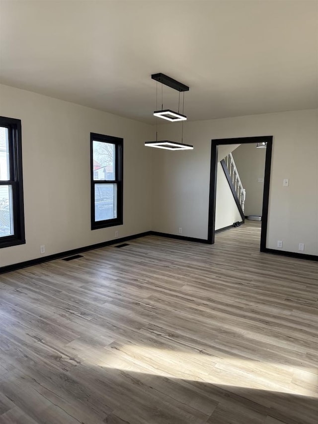 spare room with visible vents, wood finished floors, and baseboards