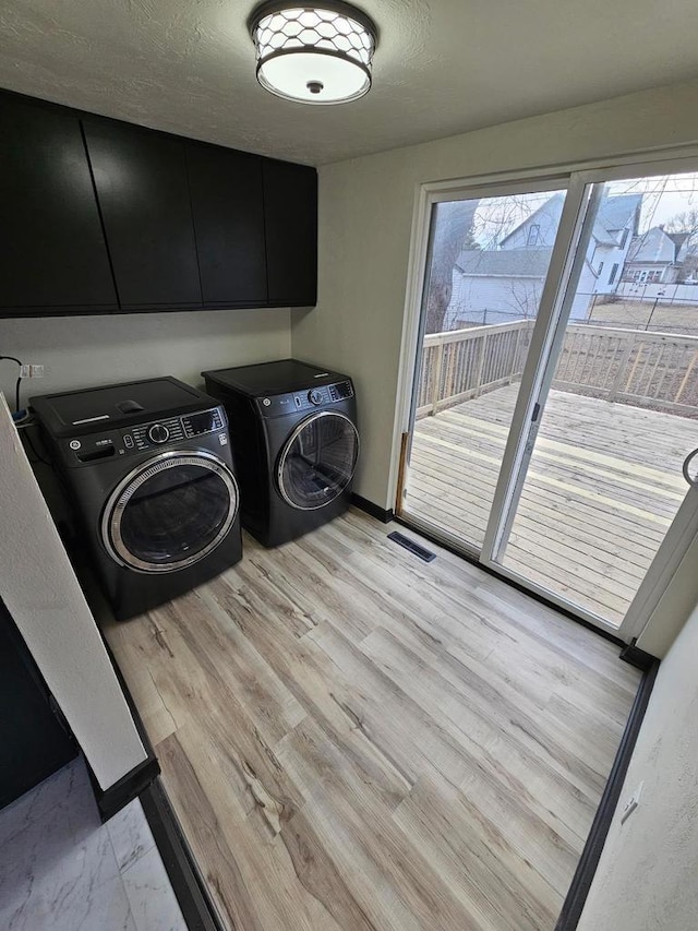 laundry area featuring visible vents, independent washer and dryer, light wood-style flooring, cabinet space, and baseboards