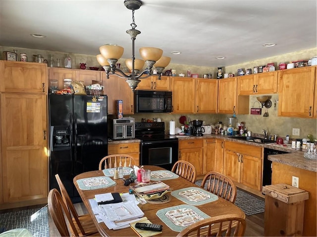 kitchen featuring decorative light fixtures, light countertops, a notable chandelier, black appliances, and a sink