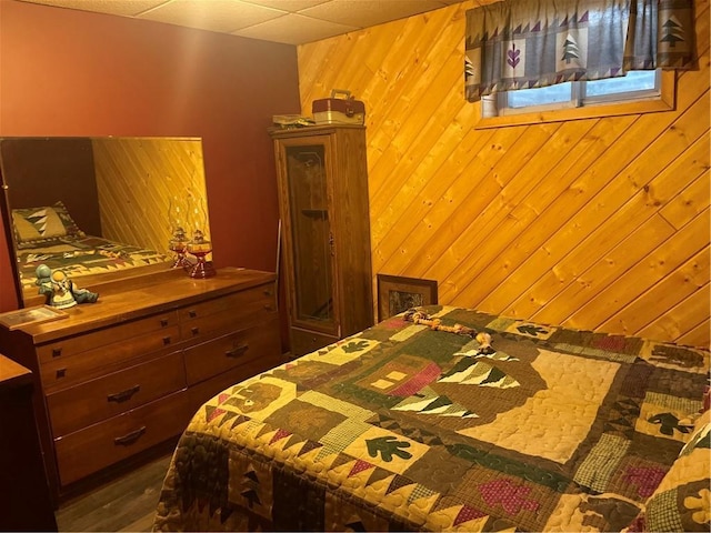 bedroom with a drop ceiling and wood walls