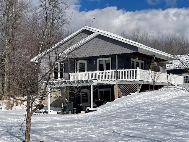 snow covered back of property featuring a deck