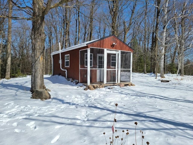 snow covered structure with an outbuilding