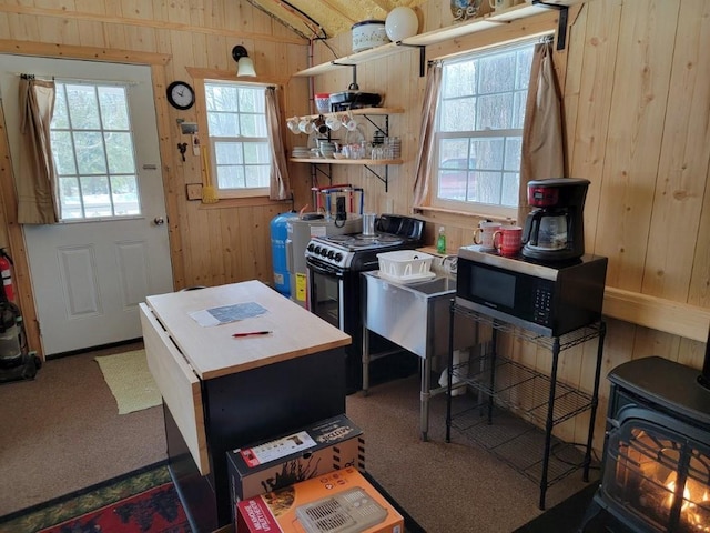 kitchen with open shelves, stainless steel microwave, a kitchen island, wooden walls, and a wood stove