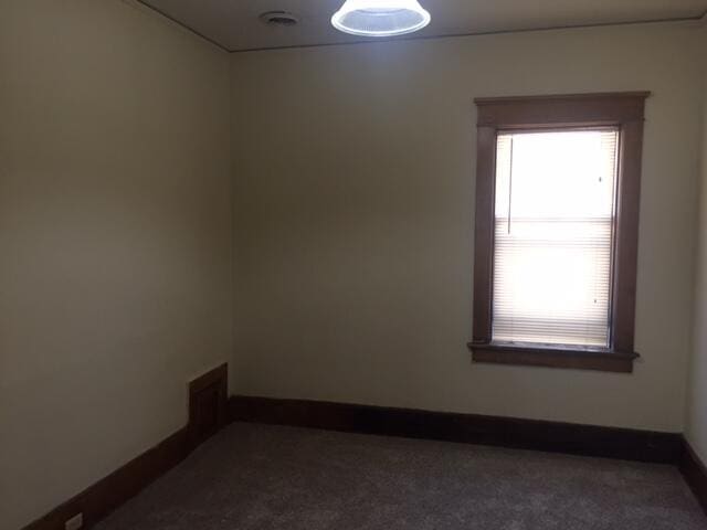 unfurnished room with dark carpet and baseboards