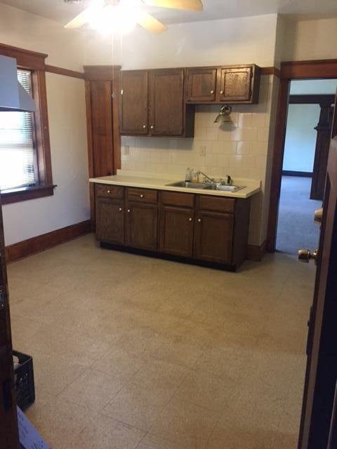 kitchen featuring a sink, tasteful backsplash, light floors, and light countertops