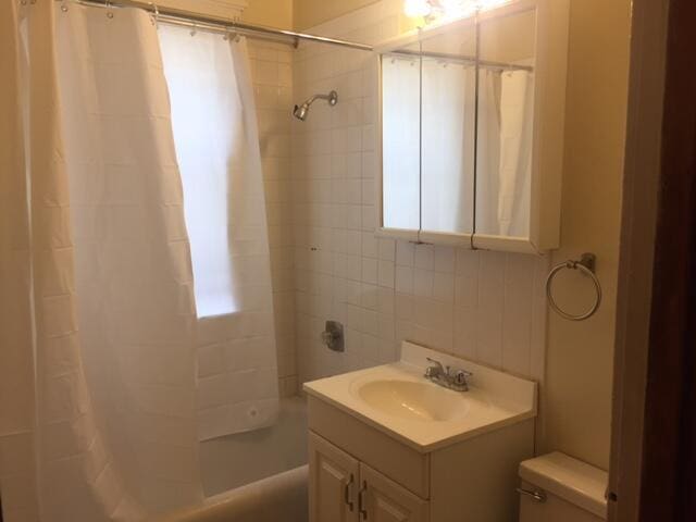 full bathroom with shower / bath combo with shower curtain, toilet, and vanity