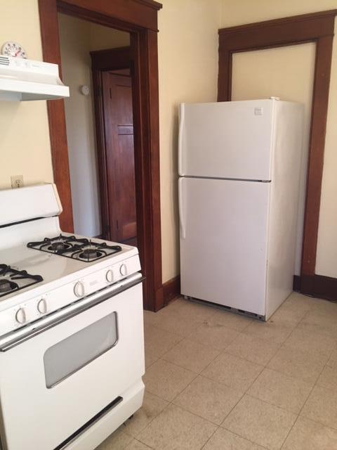 kitchen featuring under cabinet range hood, white appliances, baseboards, and light tile patterned flooring