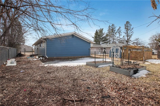 back of property featuring a garden, an outdoor structure, and fence