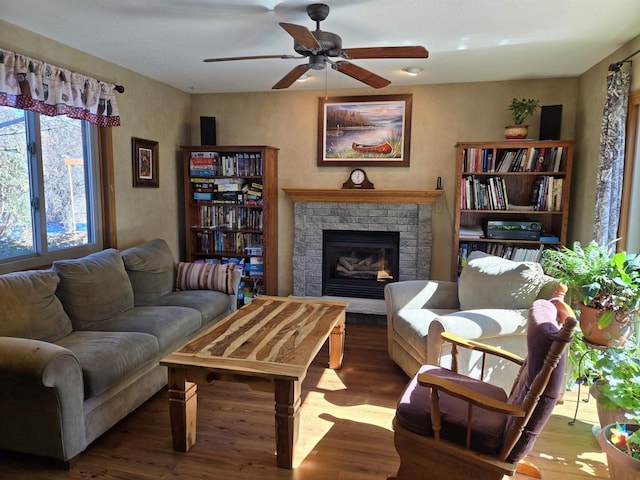 living room featuring a ceiling fan, a brick fireplace, and wood finished floors