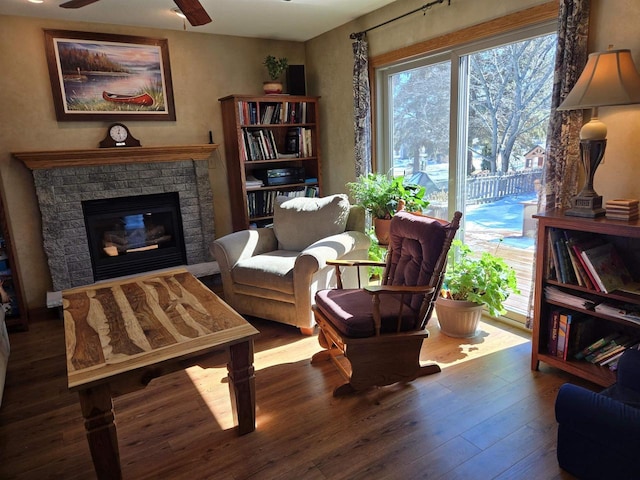 sitting room featuring ceiling fan, wood finished floors, and a fireplace