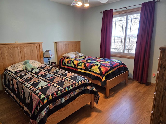 bedroom with ceiling fan, baseboards, and wood finished floors