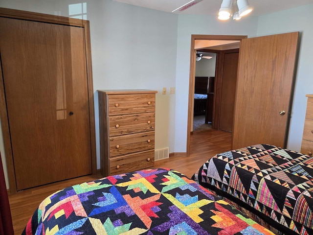 bedroom with wood finished floors, visible vents, and baseboards