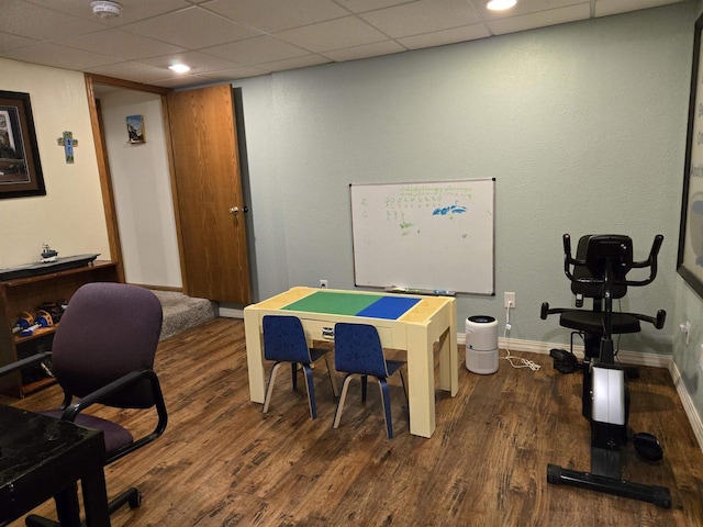 office space featuring dark wood-type flooring, a paneled ceiling, and baseboards