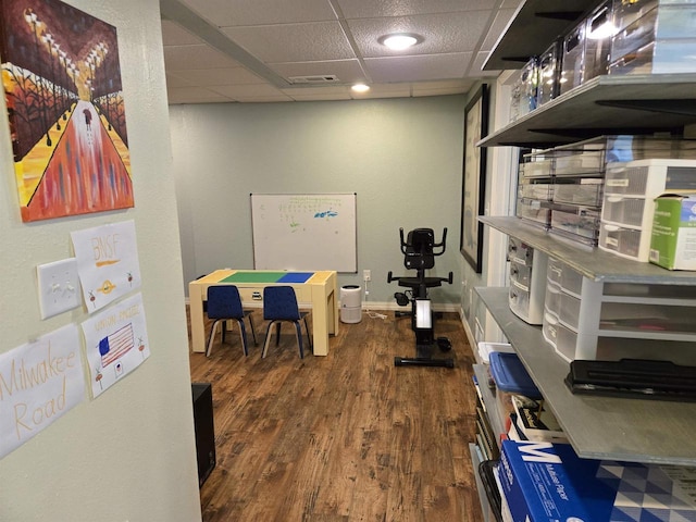 interior space with dark wood-type flooring, visible vents, baseboards, and a drop ceiling