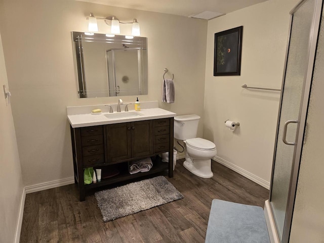 bathroom with vanity, a shower stall, toilet, and wood finished floors