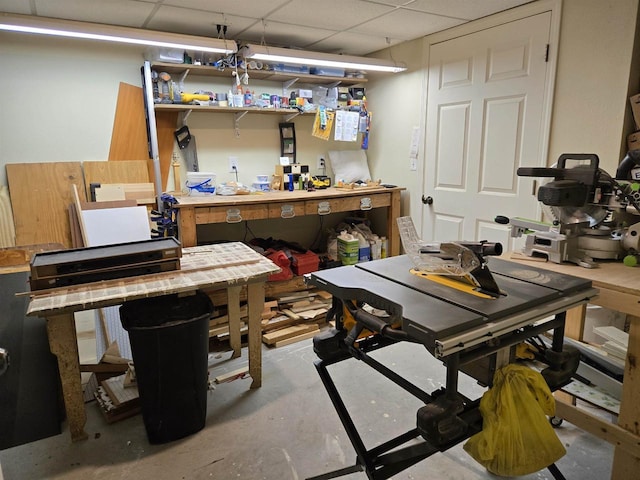 miscellaneous room with unfinished concrete floors, a workshop area, and a drop ceiling