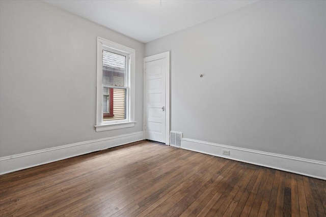 empty room with visible vents, wood-type flooring, and baseboards