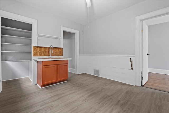 interior space with visible vents, a wainscoted wall, light countertops, wood finished floors, and a sink