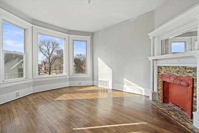 unfurnished living room with visible vents, wood-type flooring, baseboards, and a fireplace