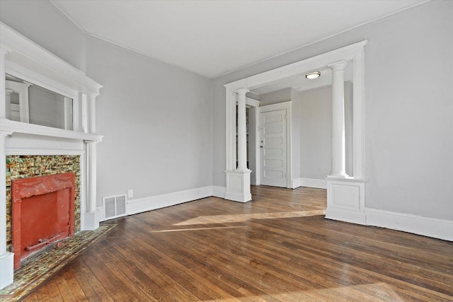 unfurnished living room featuring hardwood / wood-style floors, visible vents, ornate columns, baseboards, and a fireplace