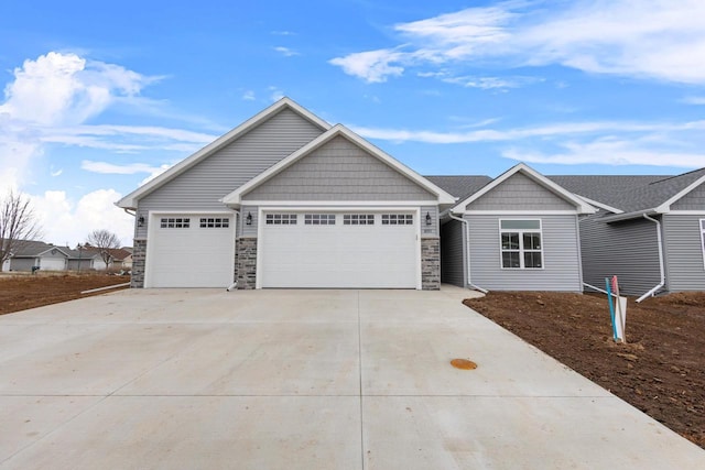 craftsman house featuring a garage, stone siding, and concrete driveway