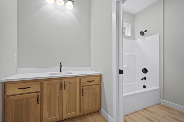 bathroom featuring vanity, shower / tub combination, wood finished floors, and baseboards