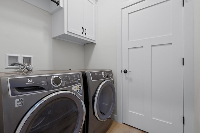 laundry room with washer and dryer, cabinet space, and light wood-style flooring