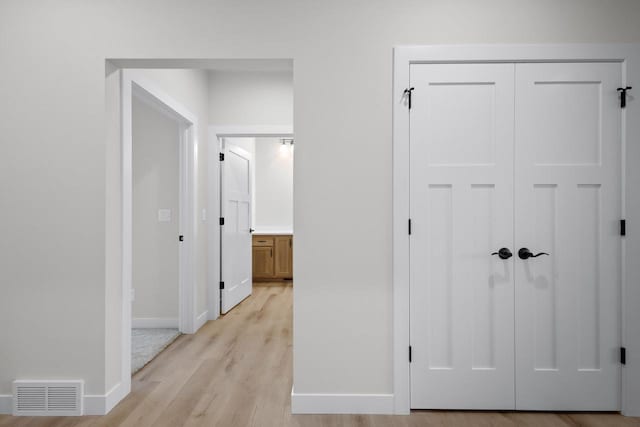 hall featuring visible vents, light wood-style flooring, and baseboards