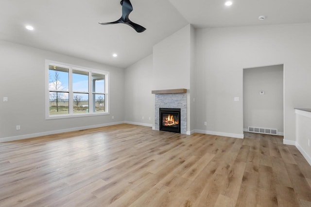 unfurnished living room with a ceiling fan, visible vents, baseboards, a fireplace, and light wood-style floors